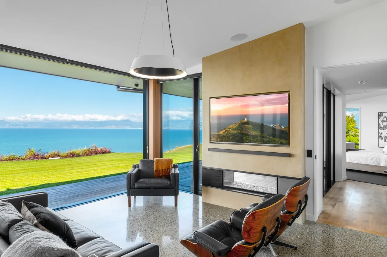 Living room with glass doors opening to the lawn and bay, artwork and a fireplace